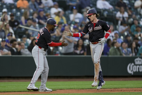 Washington Nationals' Robert Hassell III, right, celebrates his first career home run with third base coach Ricky Gutierrez during the eighth inning of a baseball game against the Seattle Mariners Wednesday, May 28, 2025, in Seattle. (AP Photo/Ryan Sun)