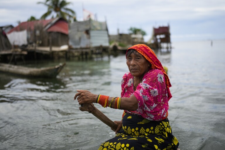 Cecilia Henry paddles a boat along the shore of Gardi Sugdub Island, part of the San Blas archipelago off Panama's Caribbean coast, Saturday, May 25, 2024. Due to rising sea levels, about 300 Guna Indigenous families will relocate to new homes, built by the government, on the mainland. (AP Photo/Matias Delacroix)