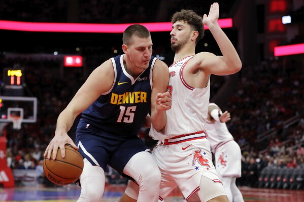 Denver Nuggets center Nikola Jokic (15) drives into Houston Rockets center Alperen Sengun, right, during the first half of an NBA basketball In-Season Tournament game Friday, Nov. 24, 2023, in Houston. (AP Photo/Michael Wyke)