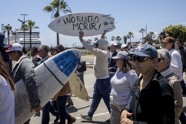 A demonstrator holding a bodyboard written in Spanish " I don't want to die" protests the disappearance of foreign surfers in Ensenada, Mexico, Sunday, May 5, 2024. Mexican authorities said Friday that three bodies were recovered in an area of Baja California near where two Australians and an American went missing last weekend during an apparent camping and surfing trip. (AP Photo/Karen Castaneda)