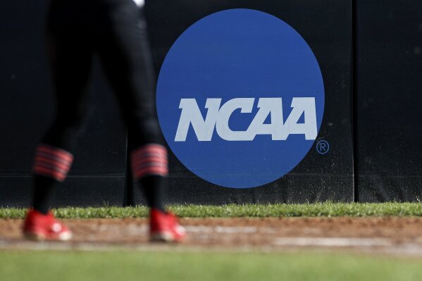 FILE - In this April 19, 2019, file photo, an athlete stands near a NCAA logo during a softball game in Beaumont, Texas. California will let college athletes hire agents and make money from endorsements, defying the NCAA and setting up a likely legal challenge that could reshape U.S. amateur sports. (AP Photo/Aaron M. Sprecher, File)