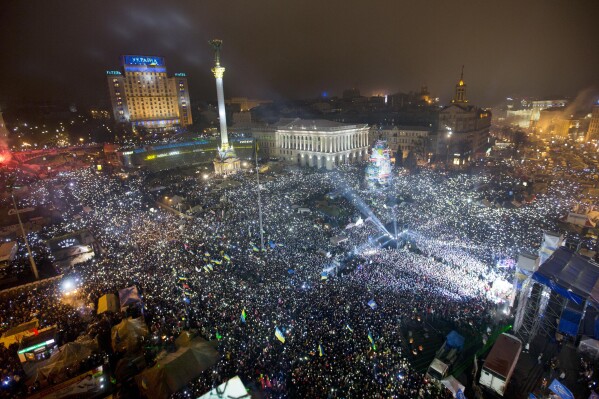 FILE - In this Jan. 1, 2014, file photo Pro-European Union activists hold lights as they sing the Ukrainian national anthem, celebrating the New Year in Kyiv's main square. At least 100,000 Ukrainians gathered in a sign of support for integration with Europe. On Nov. 21, 2023, Ukraine marks the 10th anniversary of the uprising that eventually led to the ouster of the country’s Moscow-friendly president. (AP Photo/Efrem Lukatsky, file)