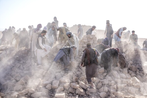 Afghan volunteers clean up rubble after an earthquake in Zenda Jan district in Herat province, western Afghanistan, Wednesday, Oct. 11, 2023. (AP Photo/Ebrahim Noroozi)