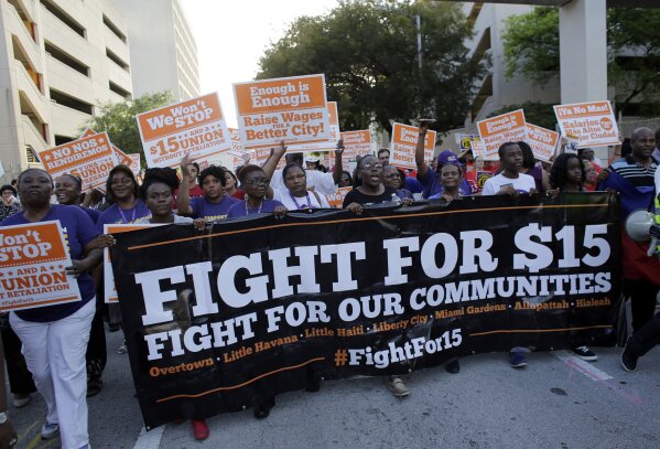 FILE - In this April 15, 2015, file photo, protesters march in support of raising the minimum wage to $15 an hour as part of an expanding national movement known as Fight for 15, in Miami. A national coalition of labor unions, along with racial and social justice organizations, will stage a mass walkout from work July 20, 2020, as part of an ongoing reckoning on systemic racism and police brutality in the U.S. (AP Photo/Lynne Sladky, File)