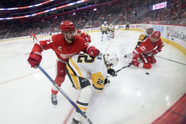 Detroit Red Wings center Dylan Larkin, left, and left wing Lucas Raymond battle for the puck with Pittsburgh Penguins right wing Sam Poulin, left, and defenseman Ryan Shea during the first period of a preseason NHL hockey game, Tuesday, Sept. 23, 2023, in Detroit. (David Guralnick/Detroit News via AP)