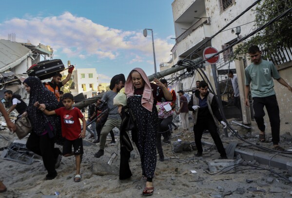 Palestinian families rush out of their homes after Israeli airstrikes target their neighborhood in Gaza City, central Gaza Strip, Tuesday, Oct. 17, 2023. (AP Photo/Abed Khaled)
