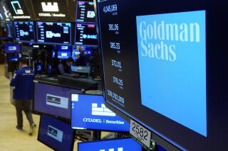 FILE - The logo for Goldman Sachs appears above a trading post on the floor of the New York Stock Exchange, Tuesday, July 13, 2021.  Goldman Sachs’ said, Tuesday, Jan. 18, 2022, its fourth-quarter profits fell by 13% from a year earlier, largely due to the bank preparing to pay out hefty pay packages to its well-compensated employees. It’s the latest sign that wages are increasing sharply, particularly on Wall Street.   (AP Photo/Richard Drew)