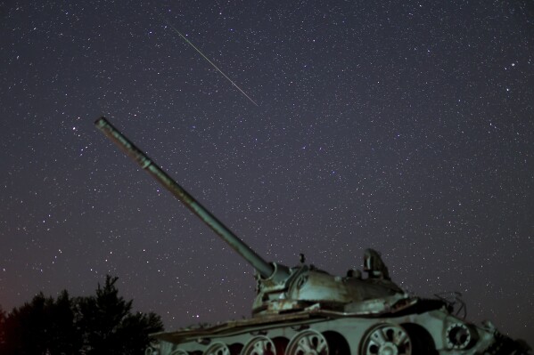 A meteor streaks above a destroyed tank from the 1992-1995 war in Bosnia, during the Perseid meteor shower on Bjelasnica mountain, Bosnia, Tuesday, Aug. 13, 2024. (AP Photo/Armin Durgut)