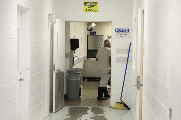In this photo taken Sept. 10, 2019, a detainee works in a kitchen area at the GEO Group’s immigration jail in Tacoma, Wash., during a media tour. After nearly four years of litigation and pandemic-related delays, a federal jury on Tuesday, June 15, 2021, began deliberating whether the GEO Group must pay minimum wage to detainees who perform cooking, cleaning and other tasks at the facility – instead of the $1 per day they typically receive. (AP Photo/Ted S. Warren)