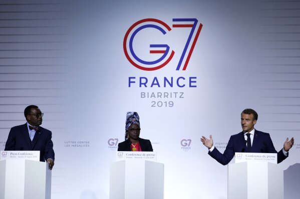 FILE - In this Sunday Aug. 25, 2019 file photo French President Emmanuel Macron, right, African Development Bank President Akinwumi Adesina, left, and UNICEF ambassador Angelique Kidjo attend a press conference on the situation in Sahel during the G7 summit in Biarritz, southwestern France. One of Africa's iconic artists, Kiddo, is the voice of a new project aimed at rewriting laws across the African continent that keep millions of women from becoming a more powerful economic force. (Ian Langsdon Pool via AP, File)