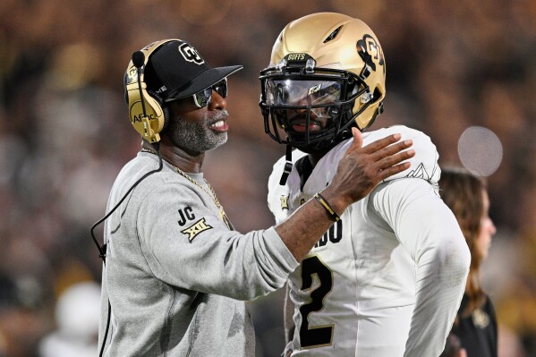 Colorado head coach Deion Sanders, left, talks with quarterback Shedeur Sanders (2) during a timeout in the second half of an NCAA college football game against Central Florida, Saturday, Sept. 28, 2024, in Orlando, Fla. (AP Photo/Phelan M. Ebenhack, File)