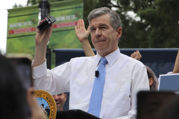 FILE - North Carolina Democratic Gov. Roy Cooper affixes his veto stamp at a public rally, May 13, 2023, in Raleigh, N.C. Gov. Cooper announced his veto Thursday, Aug. 24, of a sweeping elections bill that would end a grace period for counting mailed absentee ballots, toughen same-day registration rules and empower partisan observers at polling places. (AP Photo/Hannah Schoenbaum, file)