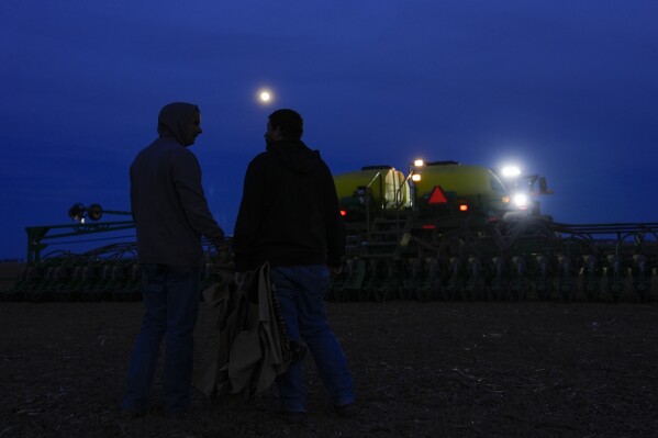 Mark Woodruff, left, and his brother, Ross, right, talk while planting soybeans, Monday, April 22, 2024, in Sabina, Ohio. When farmers have to wait for fields to dry out, already long planting days can become endurance tests that stretch into the night. (AP Photo/Joshua A. Bickel)