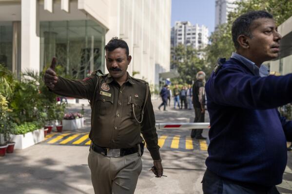 A police officer and a private security guard ask journalists to leave from the gate of a building housing BBC office in New Delhi, India, Tuesday, Feb. 14, 2023. Officials from India's Income Tax department began conducting searches Tuesday at the BBC's offices in the capital, New Delhi, three of the broadcaster's staff members told the Associated Press. (AP Photo/Altaf Qadri)