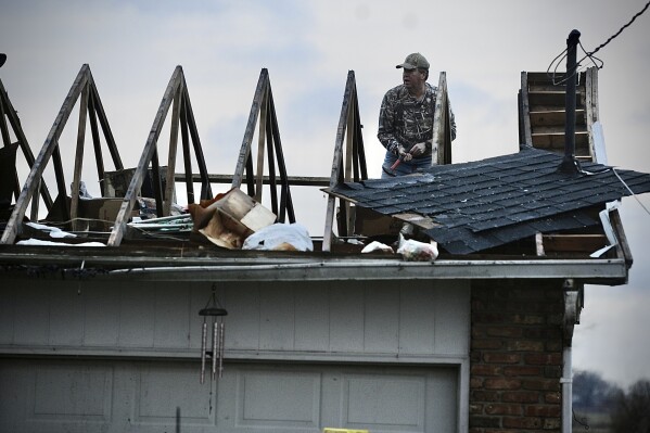 Ted Williams works to put a temporary cover on the roof of his in-laws home following a severe storm near Springfield, Ohio Wednesday morning, February 28, 2024. William said his in-laws stayed in the middle hallway and both are safe. Warning sirens jolted residents of central Ohio awake as a possible tornado hit near Columbus. Significant damage was reported at an airport in Madison County, between Dayton and Columbus. (Marshall Gorby/Dayton Daily News via AP)