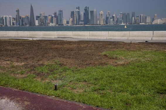 FILE - A water sprinkler on the corniche, overlooking the skyline of Doha, Qatar, Wednesday, Oct. 19, 2022. World Cup host Qatar is among the world's most water-stressed countries. But it's a problem the tiny, wealthy Persian Gulf emirate has largely paid its way out of, thanks to expensive technology known as desalination that makes seawater drinkable. (AP Photo/Nariman El-Mofty, File)