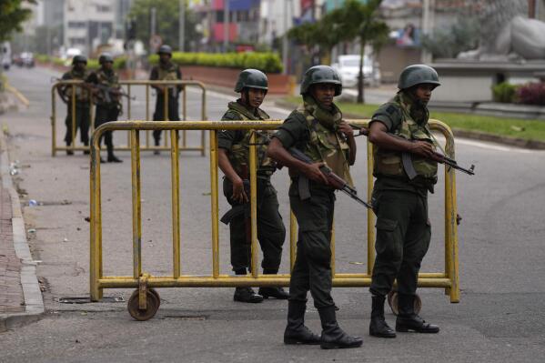 Sri Lankan army soldiers guard a check point outside prime minister's residence a day after clashes between government supporters and anti-government protesters in Colombo, Sri Lanka, Tuesday, May 10, 2022. Defying a nationwide curfew in Sri Lanka, several hundred protesters continued to chant slogans against the government Tuesday, a day after violent clashes saw the resignation of the prime minister who is blamed, along with his brother, the president, for leading the country into its worst economic crisis in decades. (AP Photo/Eranga Jayawardena)
