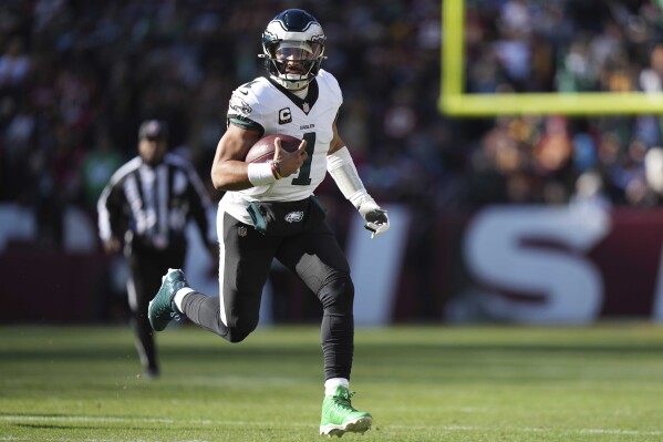 Philadelphia Eagles quarterback Jalen Hurts (1) running with the ball during the first half of an NFL football game against the Washington Commanders, Sunday, Dec. 22, 2024, in Landover, Md. (AP Photo/Stephanie Scarbrough)