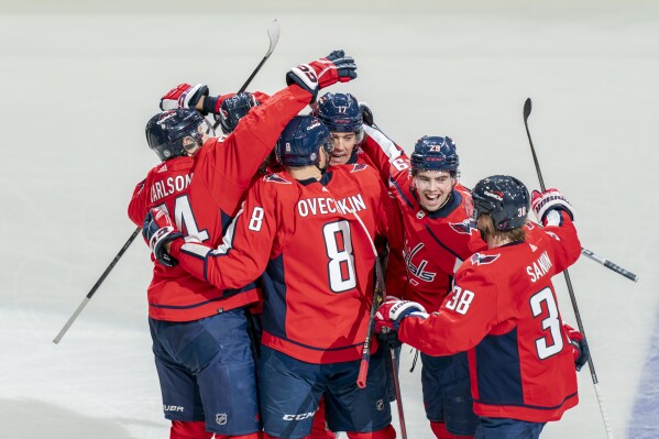 Washington Capitals celebrate after center Dylan Strome (17) scored against the New York Islanders during overtime in an NHL hockey game Wednesday, Dec. 20, 2023, in Washington. (AP Photo/Stephanie Scarbrough)