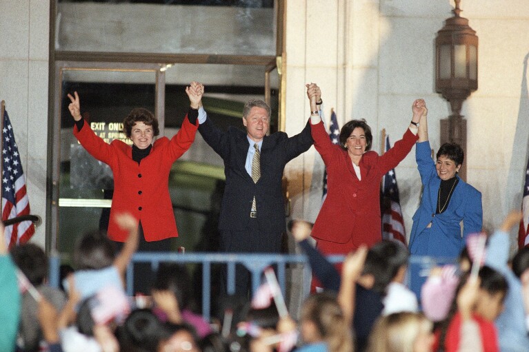 FILE - President Bill Clinton raises the arms of Democratic candidates California State Treasurer Kathleen Brown, right, and U.S. Sen. Dianne Feinstein, left, after a rally, Nov. 4, 1994, at the steps of Los Angeles City Hall. (AP Photo/Kevork Djansezian, File)