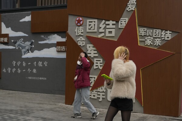 Youths walk near government propaganda in Beijing, Wednesday, Jan. 17, 2024. China published youth unemployment data Wednesday for the first time since the jobless rate hit a record high in June last year, using a new method that showed an apparent improvement. (AP Photo/Ng Han Guan)