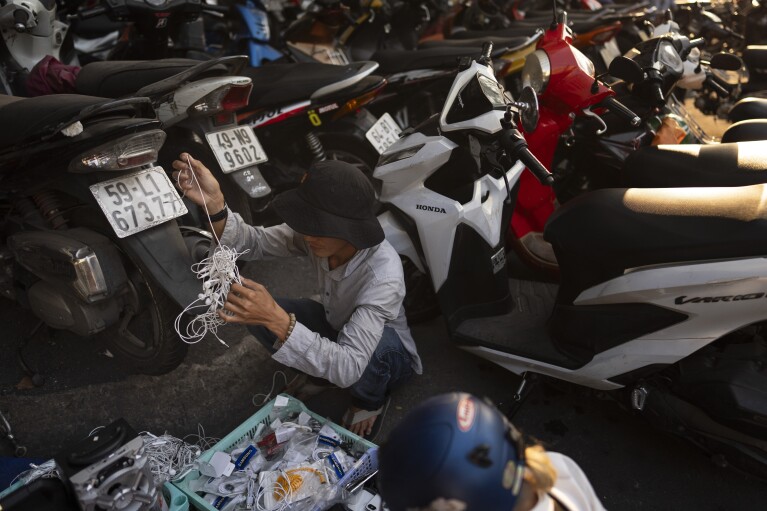 A shopper attempts to untangle used wired earphones in Nhat Tao market, the largest informal recycling market in Ho Chi Minh City, Vietnam, Wednesday, Jan. 31, 2024. (AP Photo/Jae C. Hong)