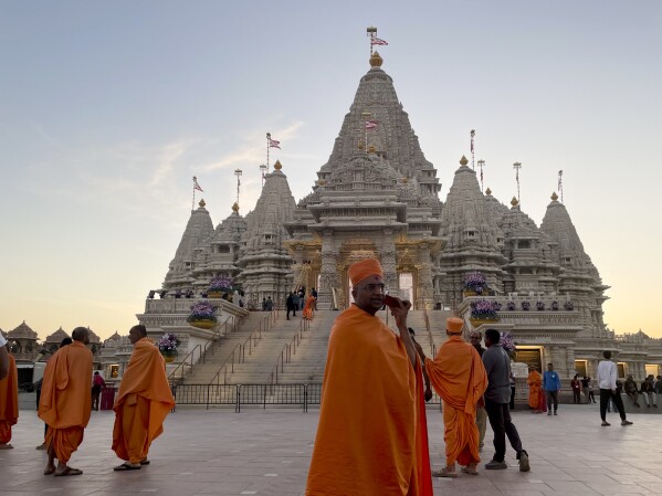 Monks in saffron robes walk in front of the BAPS Swaminarayan Akshardham, the largest Hindu temple outside India in the modern era, on Wednesday Oct. 4, 2023, in Robbinsville, N.J. The temple was partly built using marble from Italy and limestone from Bulgaria hand-carved by artisans in India and shipped to New Jersey. (AP Photo/Luis Andres Henao)