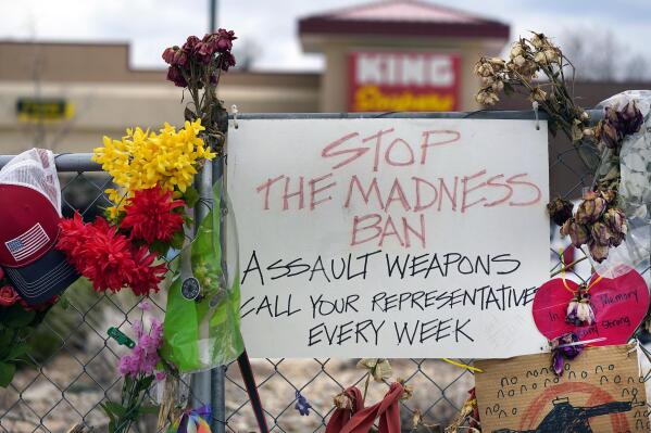 FILE - In this April 23, 2021, file photo, a sign hangs amid the tributes that cover the temporary fence around the King Soopers grocery store in which 10 people died in a mass shooting in late March in Boulder, Colo. Responding to the Colorado supermarket shooting that killed multiple people, state Democratic lawmakers have outlined bills that would create a state office dedicated to prevent gun violence, expand background checks and allow municipalities greater freedom to adopt their own gun control laws. (AP Photo/David Zalubowski, File)