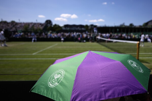 FILE - Spectators shade from the sun under an umbrella on Court 10 on day five of the Wimbledon tennis championships in London, Friday, July 7, 2023. A new monitoring service will help protect tennis players from online abuse and threats. In their joint announcement the International Tennis Federation, U.S. Tennis Association, the All England Club and the women's WTA tour say the “Threat Matrix” service will operate in 35 languages when it launches Jan. 1. (AP Photo/Alastair Grant, File)
