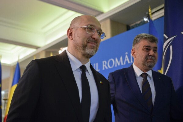 Ukrainian Prime Minister Denys Shmyhal, left, walks with Romanian counterpart Marcel Ciolacu during the welcoming ceremony at the Victoria palace, the Romanian government headquarters, in Bucharest, Romania, Friday, Aug. 18, 2023. (AP Photo/Alexandru Dobre)