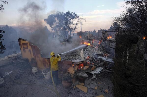 A firefighter tries to extinguish the flames at a burning house as the South Fire burns in Lytle Creek, San Bernardino County, north of Rialto, Calif., Wednesday, Aug. 25, 2021. (AP Photo/Ringo H.W. Chiu)