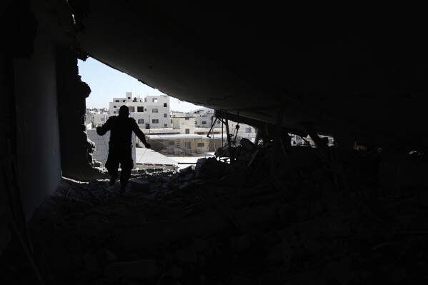 A Palestinian engineer inspects the home of a man accused of carrying out a deadly shooting attack earlier this year, after it was demlioshed by Israeli forces in the Askar refugee camp in the West Bank city of Nablus, Tuesday, Aug. 8, 2023. The Israeli military said its forces entered the camp early Tuesday and demolished the apartment of 49-year-old Abdul Fattah Kharushah, an alleged member of the Hamas militant group who was suspected of shooting and killing two Israeli brothers in the town of Hawara earlier this year. (AP Photo/Nasser Nasser)