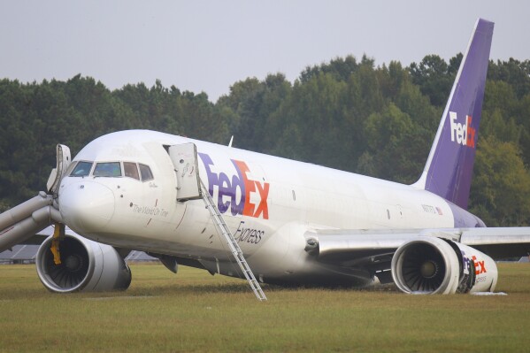 A FedEx 757 sits on a landing strip Thursday, Oct. 5, 2023 at the Chattanooga Metropolitan Airport after crash landing late Wednesday evening. Officials say the FedEx plane skidded off the runway during a crash landing when its landing gear did not descend, but no one was injured. (Olivia Ross /Chattanooga Times Free Press via AP)