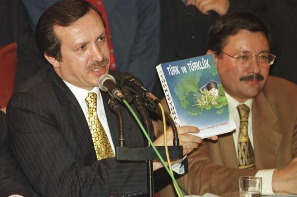 FILE - Mayor of Istanbul Recep Tayyip Erdogan holds the book called "Turk and being Turkish" as his Ankara counterpart and strongest supporter Melih Gokcek sits next to him during a press conference in Istanbul, Wednesday, April 22, 1998. Erdogan, who marked 20 years in power this year, is seeking a third consecutive term in office as Turkey’s president in elections on May 14, 2023. (AP Photo/Murad Sezer, File)
