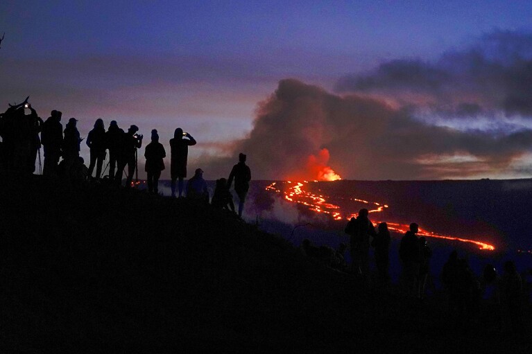 FILE - People watch and record images of lava from the Mauna Loa volcano Thursday, Dec. 1, 2022, near Hilo, Hawaii. (AP Photo/Gregory Bull, File)