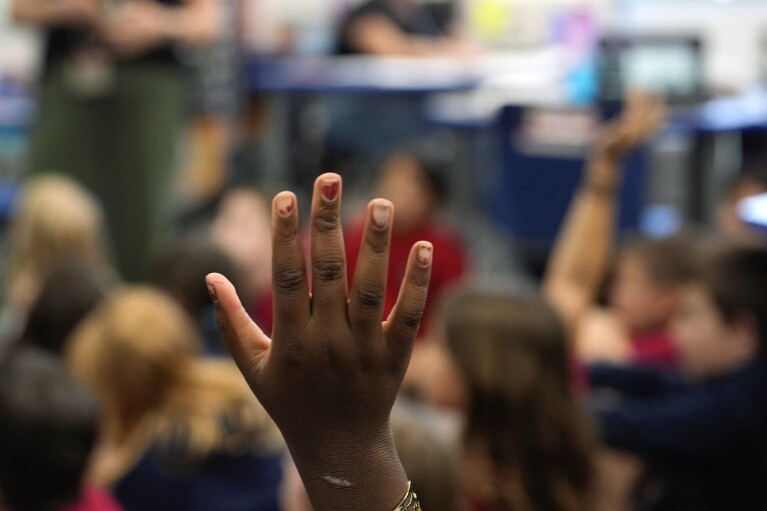 A student raises her hand to contribute in Megan Foster's third grade class, at A.D. Henderson School in Boca Raton, Fla., Tuesday, April 16, 2024. When teachers at the K-8 public school, one of the top-performing schools in Florida, are asked how they succeed, one answer is universal: They have autonomy. (AP Photo/Rebecca Blackwell)