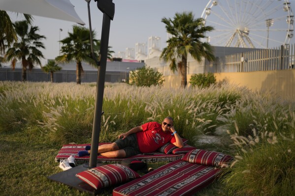 An F1 fan relaxes in the shade of an umbrella at the Formula One Bahrain Grand Prix Village at the Bahrain International Circuit in Sakhir, Bahrain, Saturday, April 12, 2025. (AP Photo/Altaf Qadri)