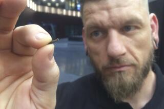 Self-described “body hacker” Jowan Osterlund from Biohax Sweden, holds a small microchip implant, similar to those implanted into workers at the Epicenter digital innovation business centre during a party at the co-working space in central Stockholm, Tuesday March 14, 2017.  Microchips are being implanted into volunteers to help them open doors and operate office equipment, and its become so popular that members of the Epicentre cyborg club hold regular parties for those with the tiny chips embedded in their hands. (AP Photo/James Brooks)