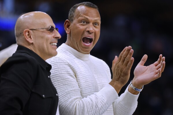 Minnesota Timberwolves and Lynx minority owners Marc Lore, left, and Alex Rodriguez cheer as a call was overturned late in the fourth quarter of the team's NBA basketball game against the Atlanta Hawks on Friday, April 12, 2024, in Minneapolis. (AP Photo/Bruce Kluckhohn)