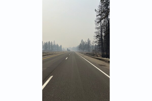 FILE - This photo provided by WSDOT East (Washington State of Transportation) smoke from wildfires fill the sky at Salnave/SR 902 interchange in Spokane County, Wash., on Saturday, Aug. 19, 2023. Authorities say a second person has died in wildfires in eastern Washington state that sparked Friday, burning hundreds of structures and closing a section of a major interstate. Fire officials said Monday, Aug. 21, a body was found in the area of the Oregon fire north of Spokane on Sunday. (WSDOT East via AP, File)