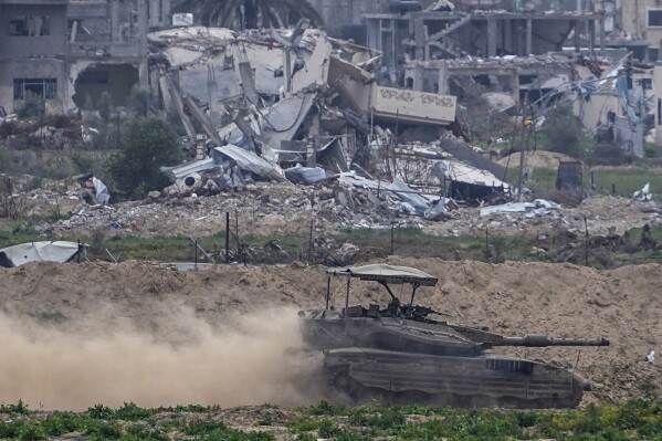 Israeli soldiers drive a tank inside the Gaza Strip, as seen from southern Israel, Tuesday, Feb. 13, 2024. The army is battling Palestinian militants across Gaza in the war ignited by Hamas' Oct. 7 attack into Israel. (AP Photo/Ariel Schalit)