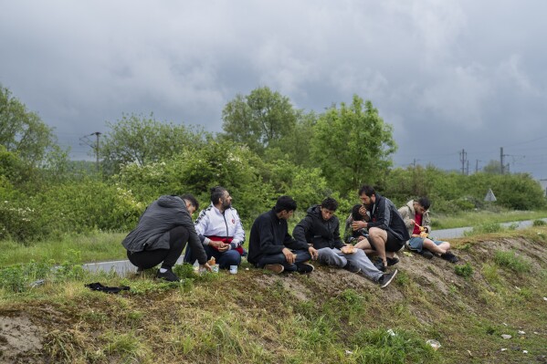 Migrants eat near a makeshift camp close to Dunkirk, in northern France, on Tuesday, May 14, 2024. (AP Photo/Bernat Armangue)