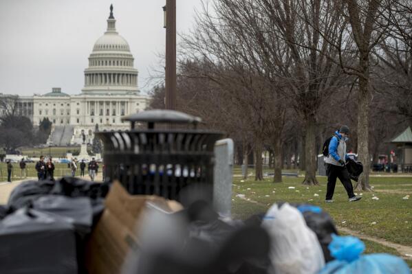 FILE - The Capitol building is visible as a man who declined to give his name, right, picks up garbage during a partial government shutdown on the National Mall in Washington, Dec. 25, 2018. All the hand-wringing over a potential government default if Congress doesn’t increase the national debt limit has conjured up images of past government shutdowns when TSA agents worked without pay and litter piled up in untended national parks. In fact, there’s a big difference between a government default and a government shutdown. (AP Photo/Andrew Harnik, File)