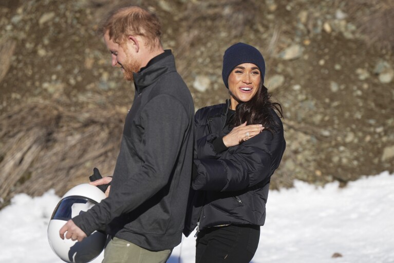 Prince Harry and Meghan Markle, the Duke and Duchess of Sussex, walk together after Harry slid down the track on a skeleton sled a second time while attending an Invictus Games training camp, in Whistler, British Columbia. Thursday, Feb. 15, 2024. (Darryl Dyck/The Canadian Press via AP)