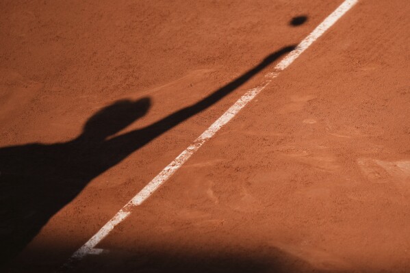 Italy's Matteo Gigante casts his shadow on the court as he serves against Ben Shelton of the U.S.during their third round match of the French Tennis Open, at the Roland-Garros stadium, in Paris, Friday, May 30, 2025. (AP Photo/Thibault Camus)