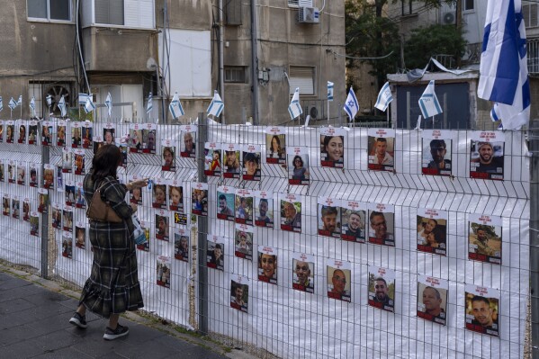 A woman looks at photographs of hostages, mostly Israeli civilians who were abducted during the Oct. 7, unprecedented Hamas attack on Israel, in Ramat Gan, Israel, Wednesday, Nov. 22, 2023. Israel and Hamas have reached an agreement for a four-day halt to the devastating war in Gaza, accompanied by the release of dozens of hostages held by the militant group in return for Palestinian prisoners jailed by Israel, mediators said Wednesday. (AP Photo/Oded Balilty)