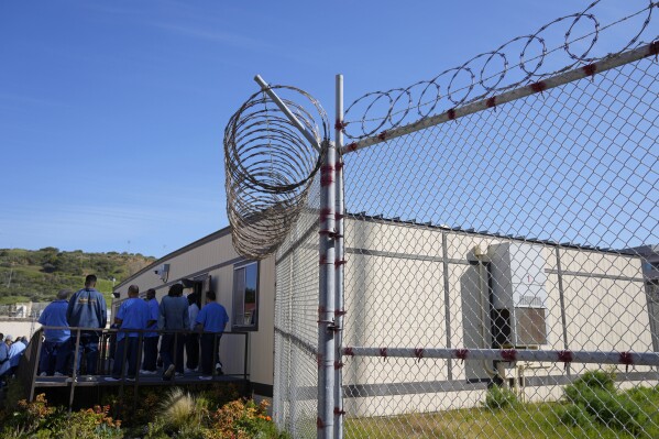 FILE - Incarerated men stand outside the classroom of the Peer Literacy Mentor Program at San Quentin State Prison in San Quentin, Calif., Friday, March 17, 2023. Californians released from prisons could receive direct cash payments along with help in job searches and other support under a first-in-the-nation program aimed at easing the transition out of incarceration and reducing recidivism. (AP Photo/Eric Risberg, File)