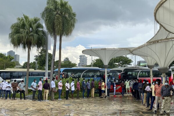 Migrant workers line up outside the Singapore Flyer Ferris Wheel attraction in Singapore on March 7, 2021. They are among at least 20,000 workers who will be treated to rides by members of the public and businesses. Migrant workers are getting a bird's eye view of Singapore, with the public's help. (AP Photo/Annabelle Liang)