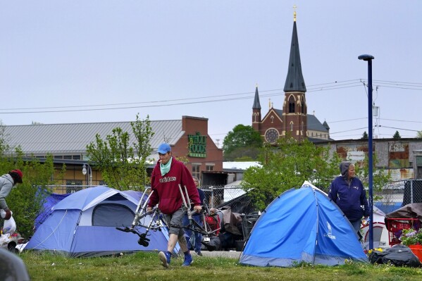 Inhabitants of a homeless camp remove their belongings after being forced to leave before city workers cleaned up the area, Tuesday, May 16, 2023, in Portland, Maine. The Portland City Council rejected the proposal by a vote of 3-6 early Tuesday, Nov. 21 morning in the wake of hours of testimony. The city is home to a large homeless population and its practice of clearing homeless encampments has drawn criticism from some advocates in the community. (AP Photo/Robert F. Bukaty)