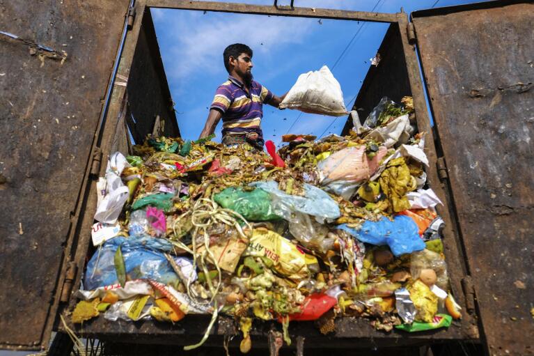 Mohammad Jewel unloads a van full of garbage at a dumpsite in the poor Mirpur area of Dhaka, Bangladesh on July 3, 2022. Jewel and Arzu Begum were forced to flee the Ramdaspur village in Bangladesh last year when the Meghna River flooded and destroyed their home. "My heart aches when I think of my village, my ancestors, my old days. I had no choice but to leave my birthplace." (AP Photo/Mahmud Hossain Opu)